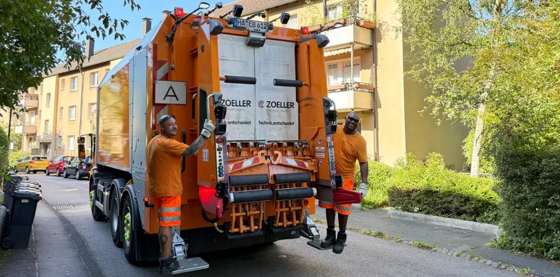 Zwei HEB-Mitarbeiter auf einem Müllwagen