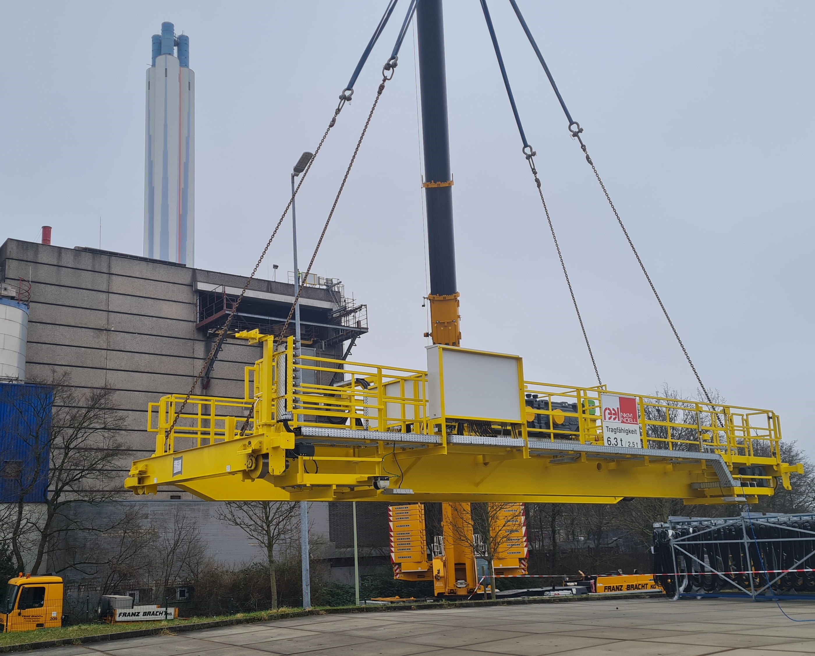 Ein Autokran hebt die neue Kranbrücke in die Anlage